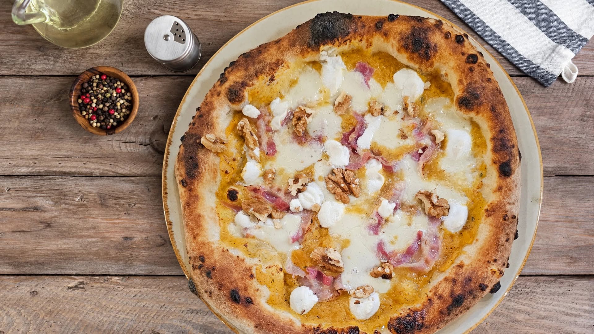 Wood-fired pizza with walnuts, mozzarella and cured meat